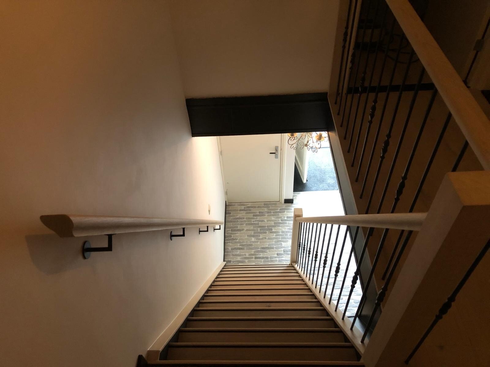 Landelijke traprenovatie met nieuwe leuningen balustrade eikenhoute met zwart sierlijke spijlen smeedijzer metaal staal zwart.jpg