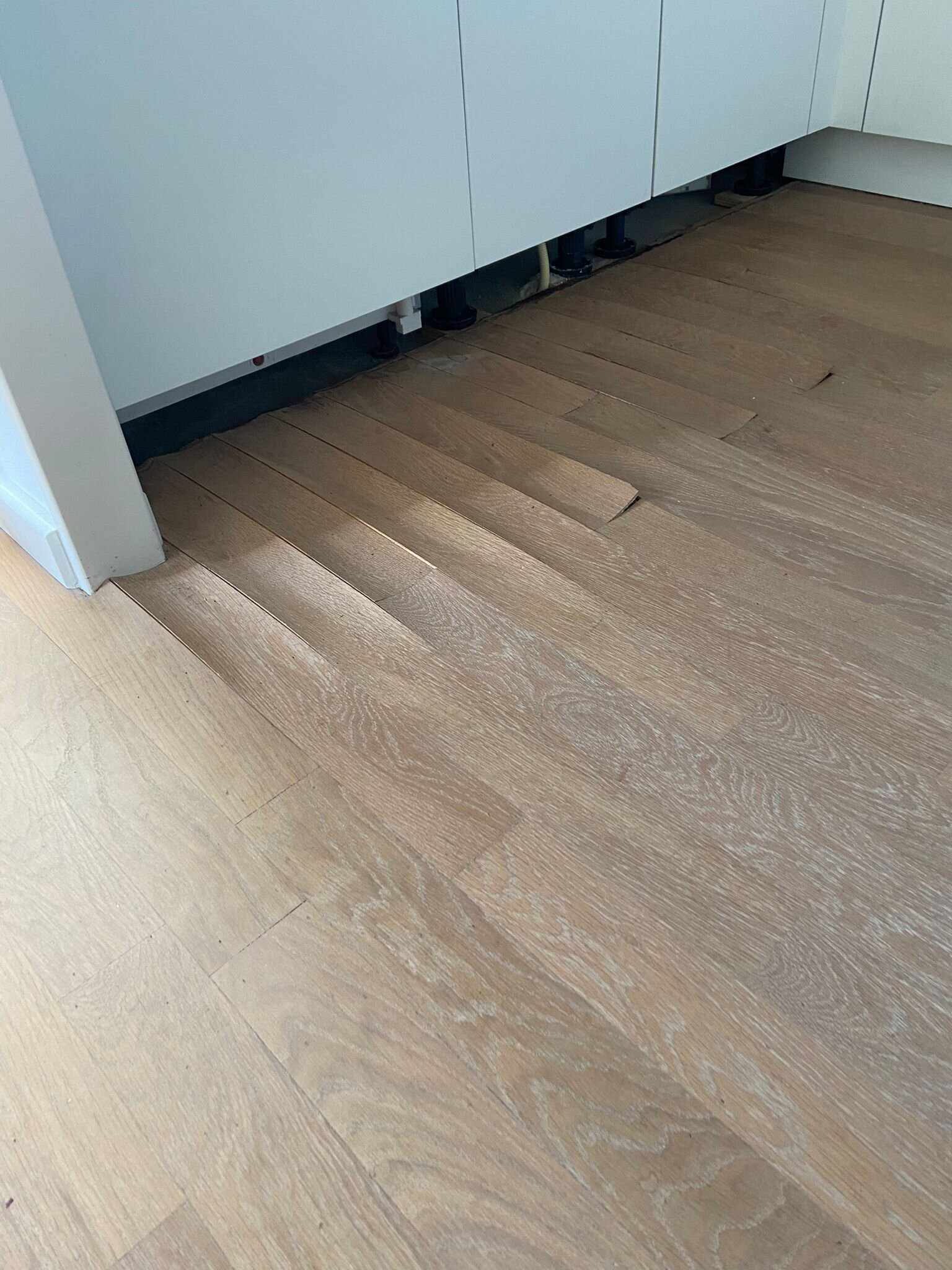 Eiken parketvloer met waterschade, krom getrokken vloerdelen, vloer staat bol