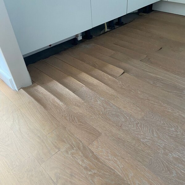 Eiken parketvloer met waterschade, krom getrokken vloerdelen, vloer staat bol