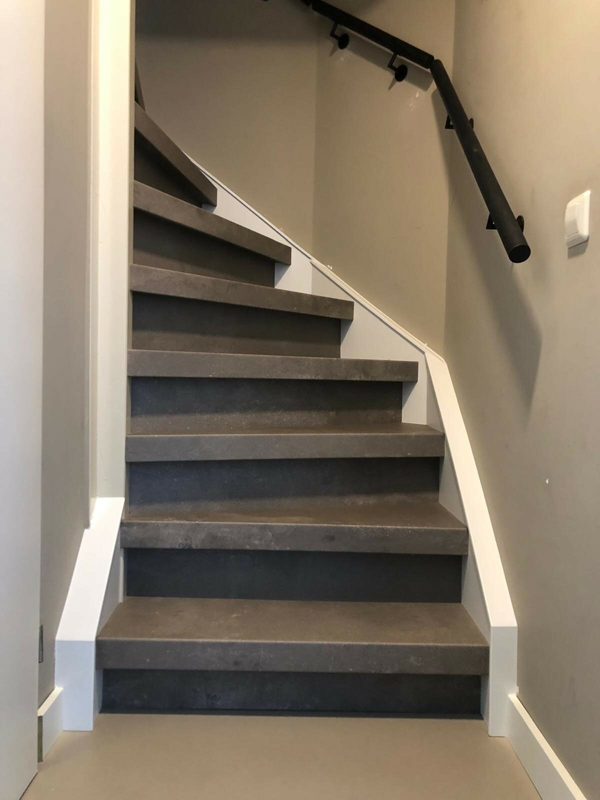 Betonlook traprenovatie greigekleur warm beige Leerdam met zijwangen en zwarte leuning.jpg